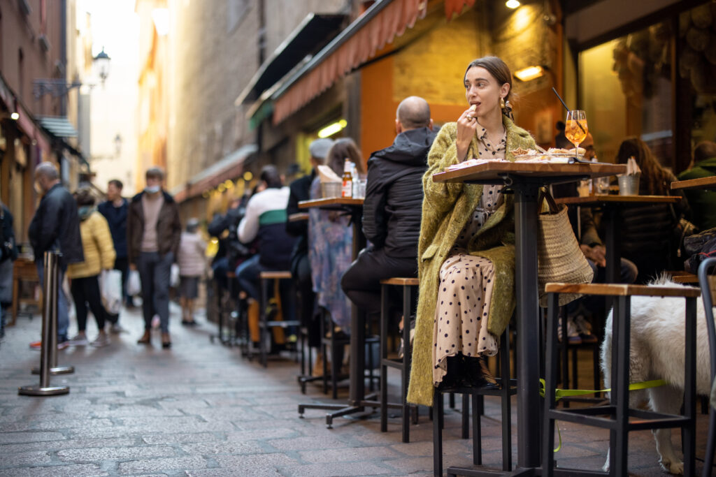 Frau sitzt an einem Stehtisch und isst eine Vorspeise. Sinnbild für Google My Business für Restaurants.