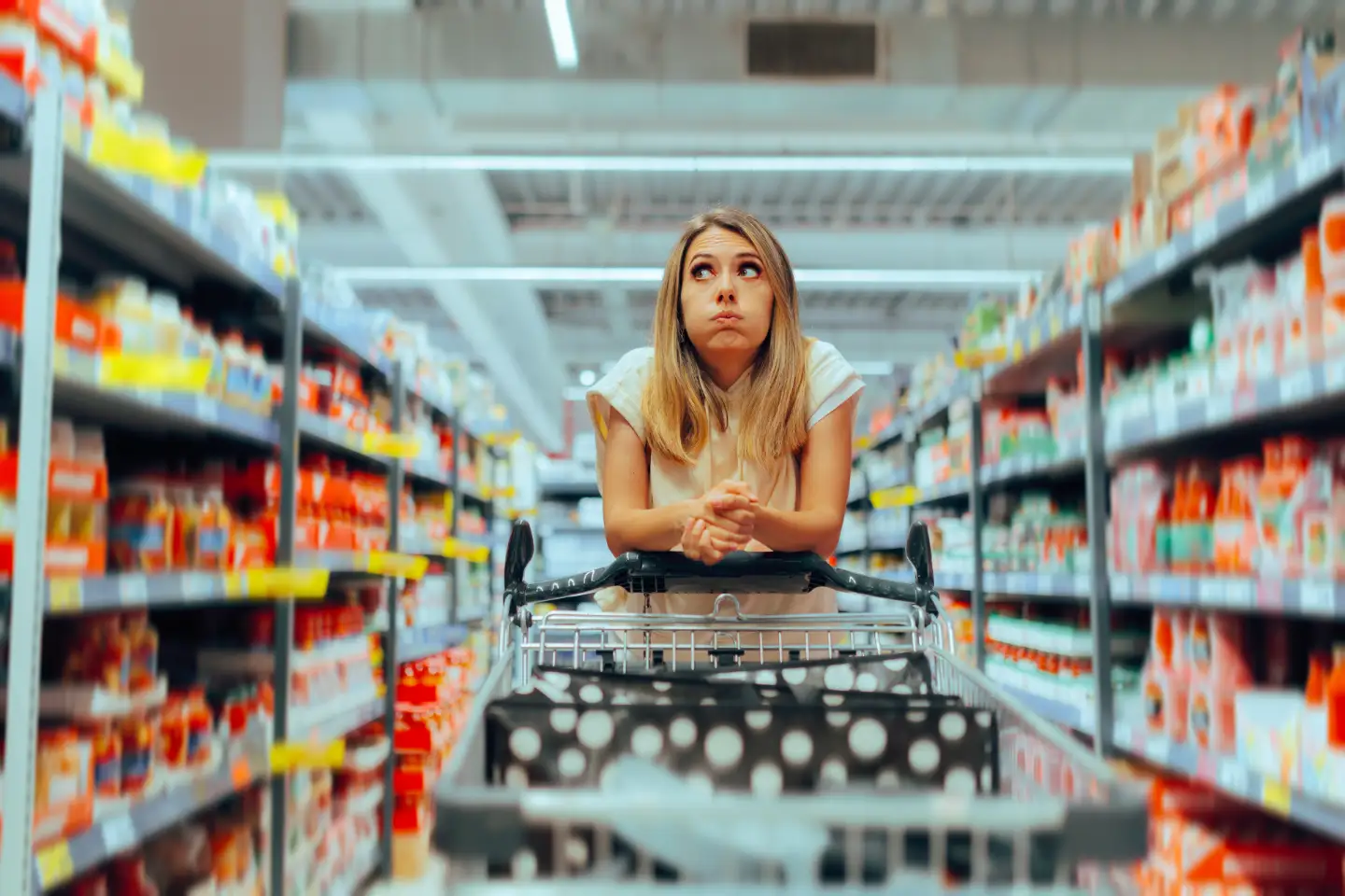 Sinnbild für Website Navigation: Frau ist im Supermarkt mit einem Einkaufswagen und sucht ihr gewünschtes Produkt.