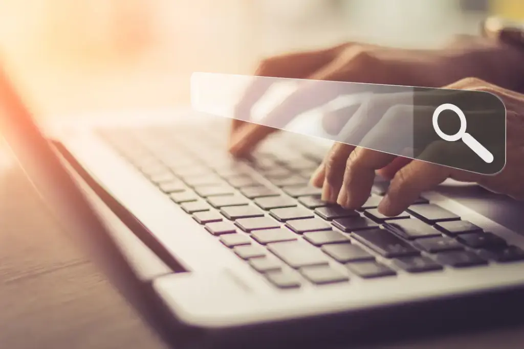 Person tippt auf Laptop, ein digitales Symbol für Suchanfrage ist sichtbar als Hinweis auf Bedeutung einer SEO-Strategie